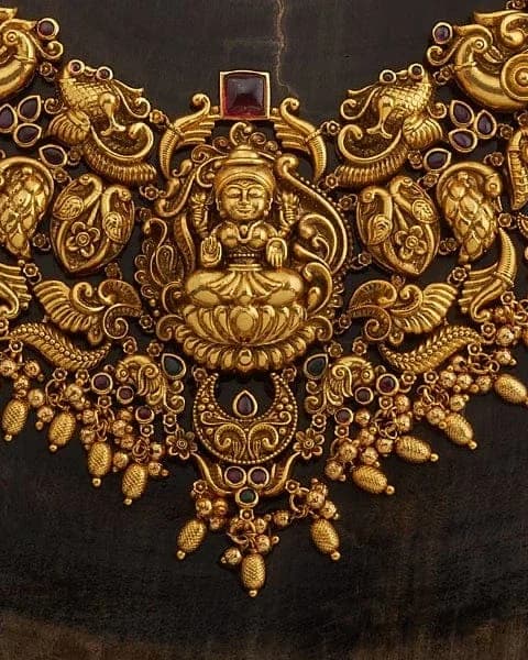 Close-up of a temple necklace with a Lakshmi motif and ruby-red stones